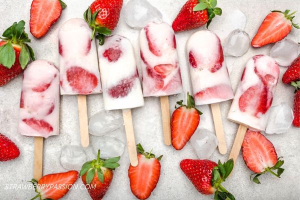 Strawberry and Cream Popsicles on platter with strawberries scatter around